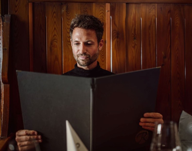 Ein Mann studiert konzentriert die Fonduekarte im Fonduerestaurant Ennshof